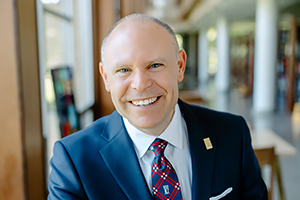 A woman in a red dress and man in a blue suit stand and smile